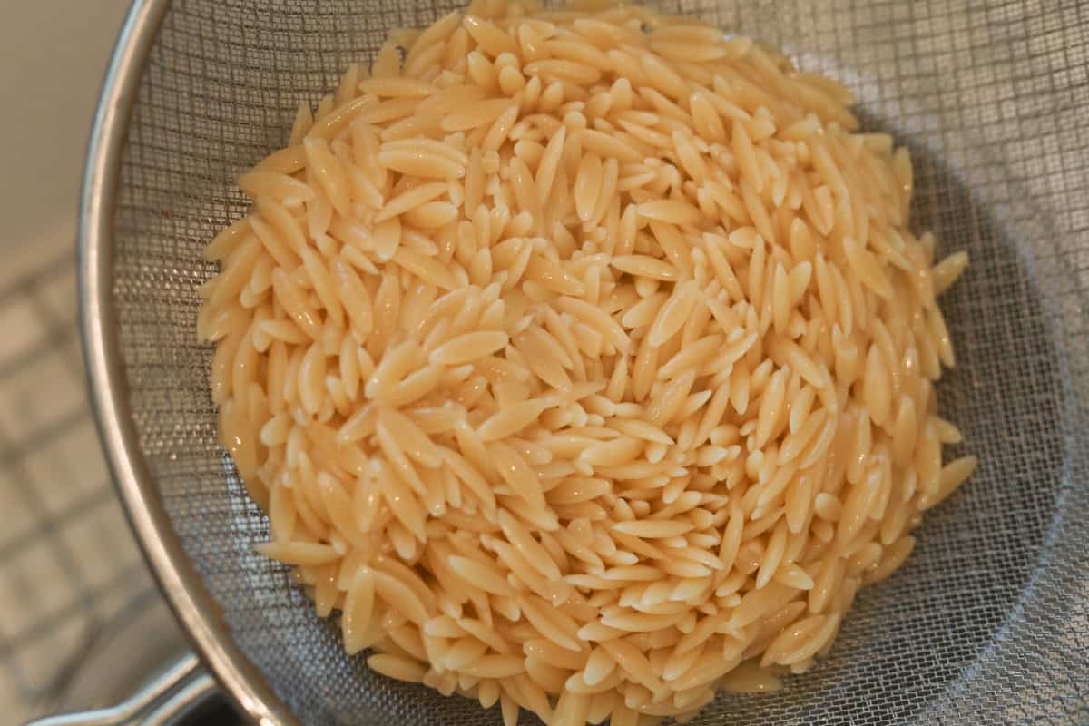 Drained orzo pasta in colander.