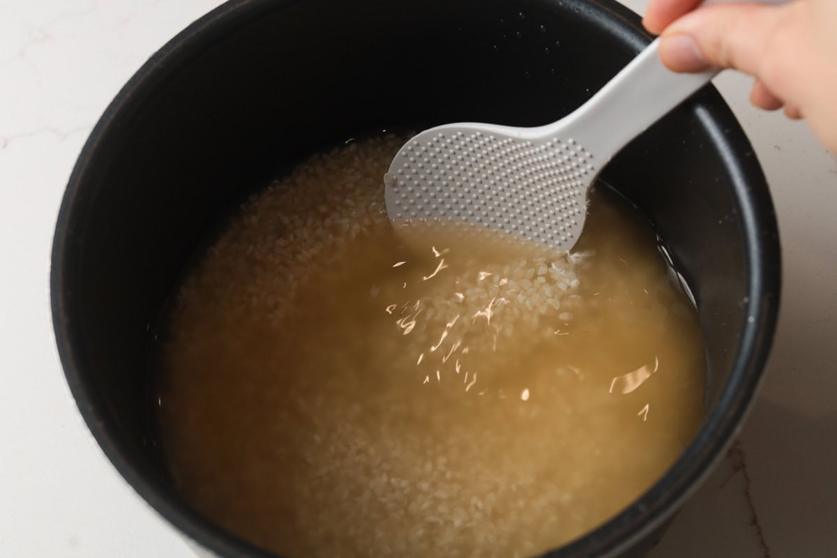 Stirring uncooked rice and water in pot.