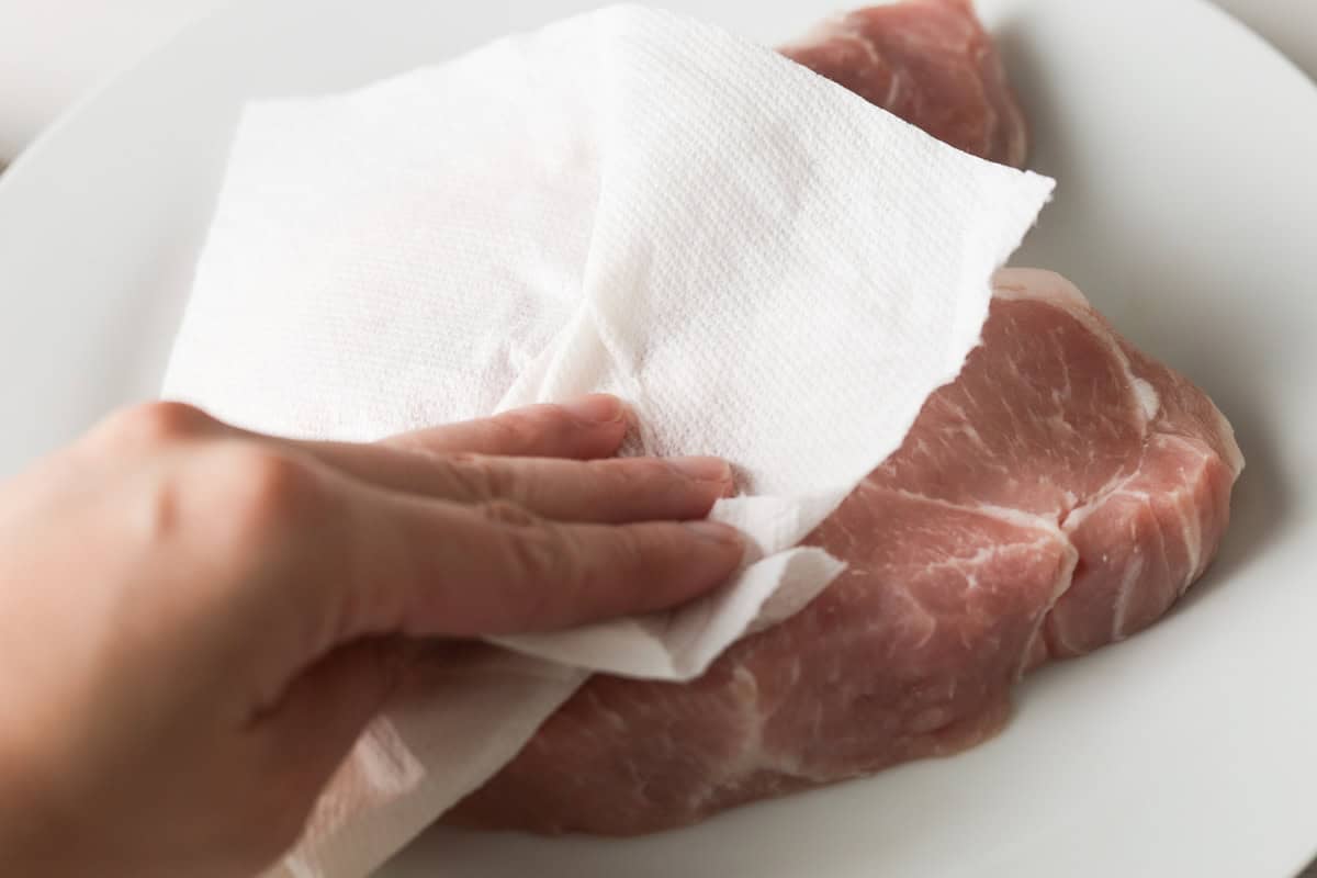 Drying pork loin chops with paper towel.