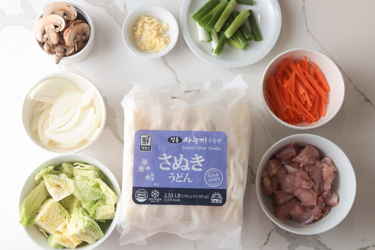 Udon, onion, cabbage, chicken, cut carrots, mushroom, garlic, green onions.