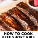 Close-up of tender oven-baked BBQ beef short ribs coated in rich barbecue sauce and garnished with fresh herbs.