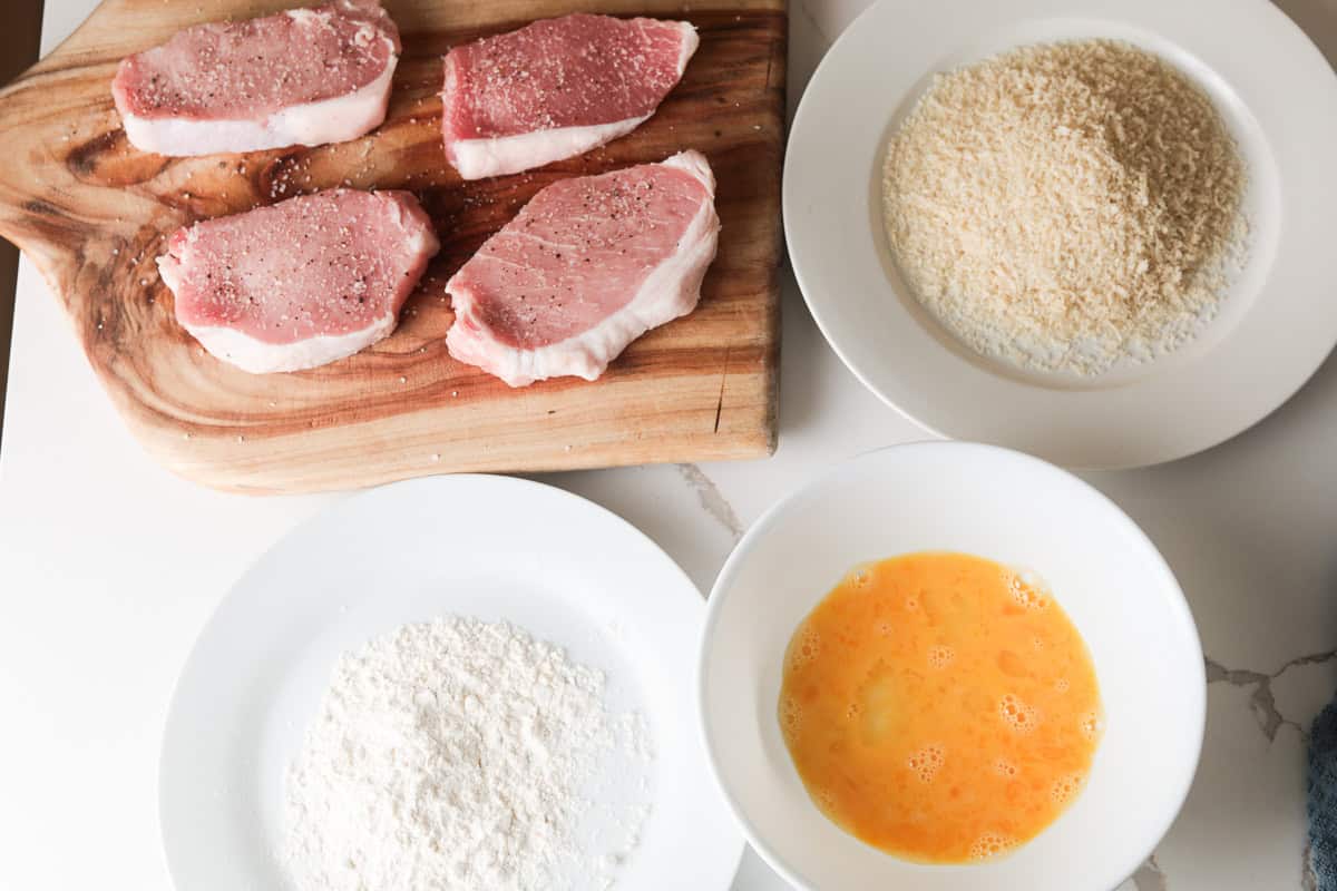 pork cutlets, flour, whisked eggs in bowl, panko bread crumbs on plate.