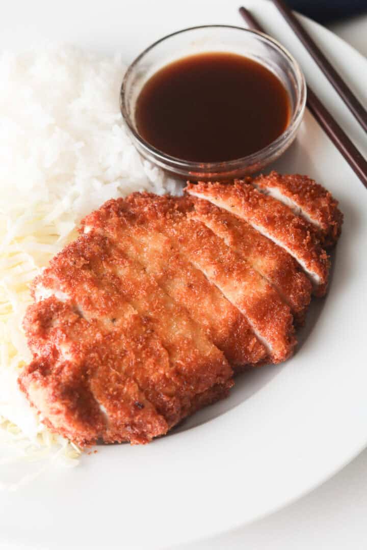 Plate rice, cabbage, pork katsu and sauce.