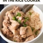 A top-down shot of a white ceramic bowl filled with tender chunks of chicken adobo and seasoned rice, garnished with fresh chopped green onions and a single bay leaf. The top of the image features bold black and red text reading "HOW TO COOK CHICKEN ADOBO IN THE RICE COOKER."