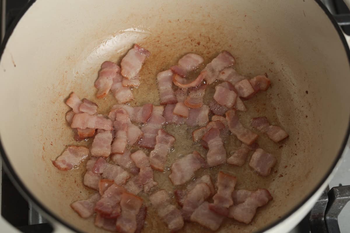 Chopped bacon frying inside a pot.