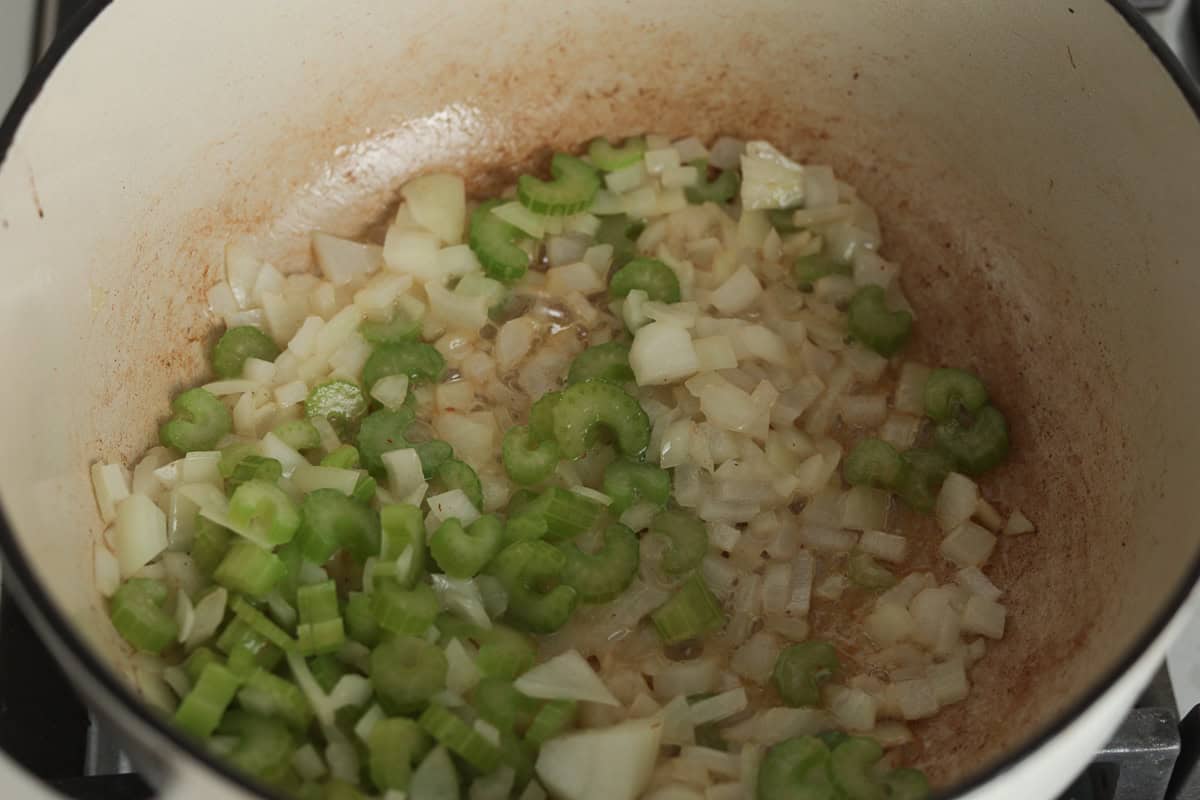 Diced onions and celery sautéing in a pot.