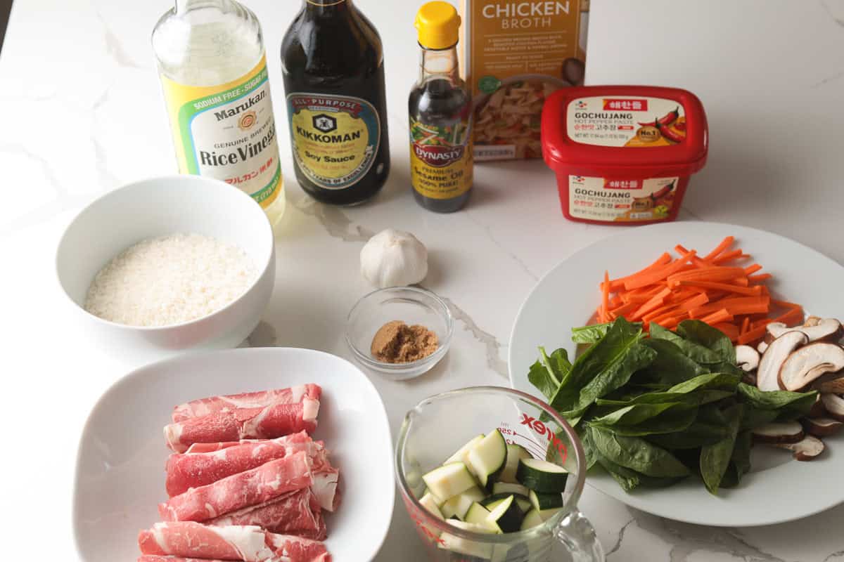 Fresh ingredients for beef bibimbap including sliced beef, vegetables, and sauces.