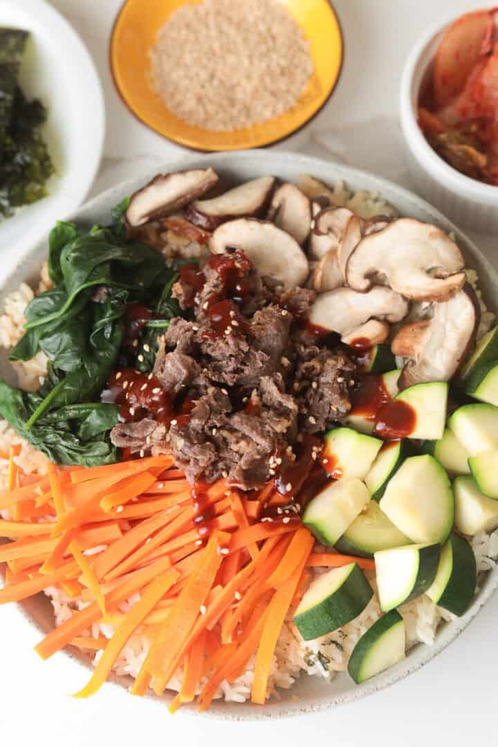 Korean beef bibimbap served with kimchi and seaweed side dishes.